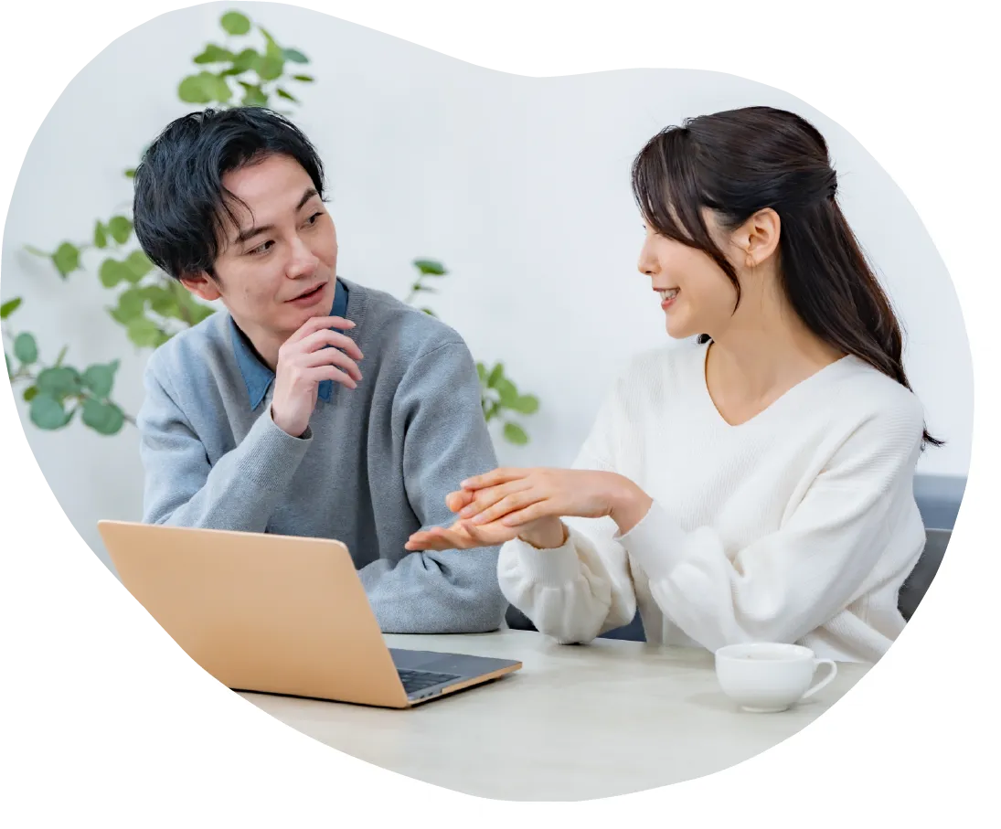 テーブル越しに男女二人がノートパソコンを前に向き合い、相談をしている様子