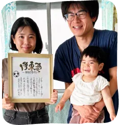 筆文字アートを、笑顔の男女が並んで持っている様子
